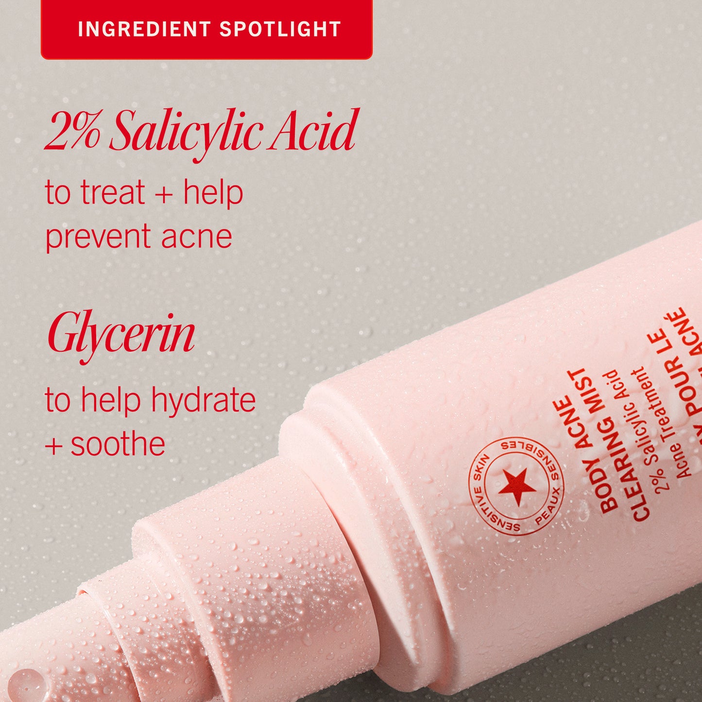A pink spray bottle labeled "Body Acne Clearing Mist" with water droplets is on a gray surface. Text highlights "2% Salicylic Acid" for acne treatment and "Glycerin" for hydration.
