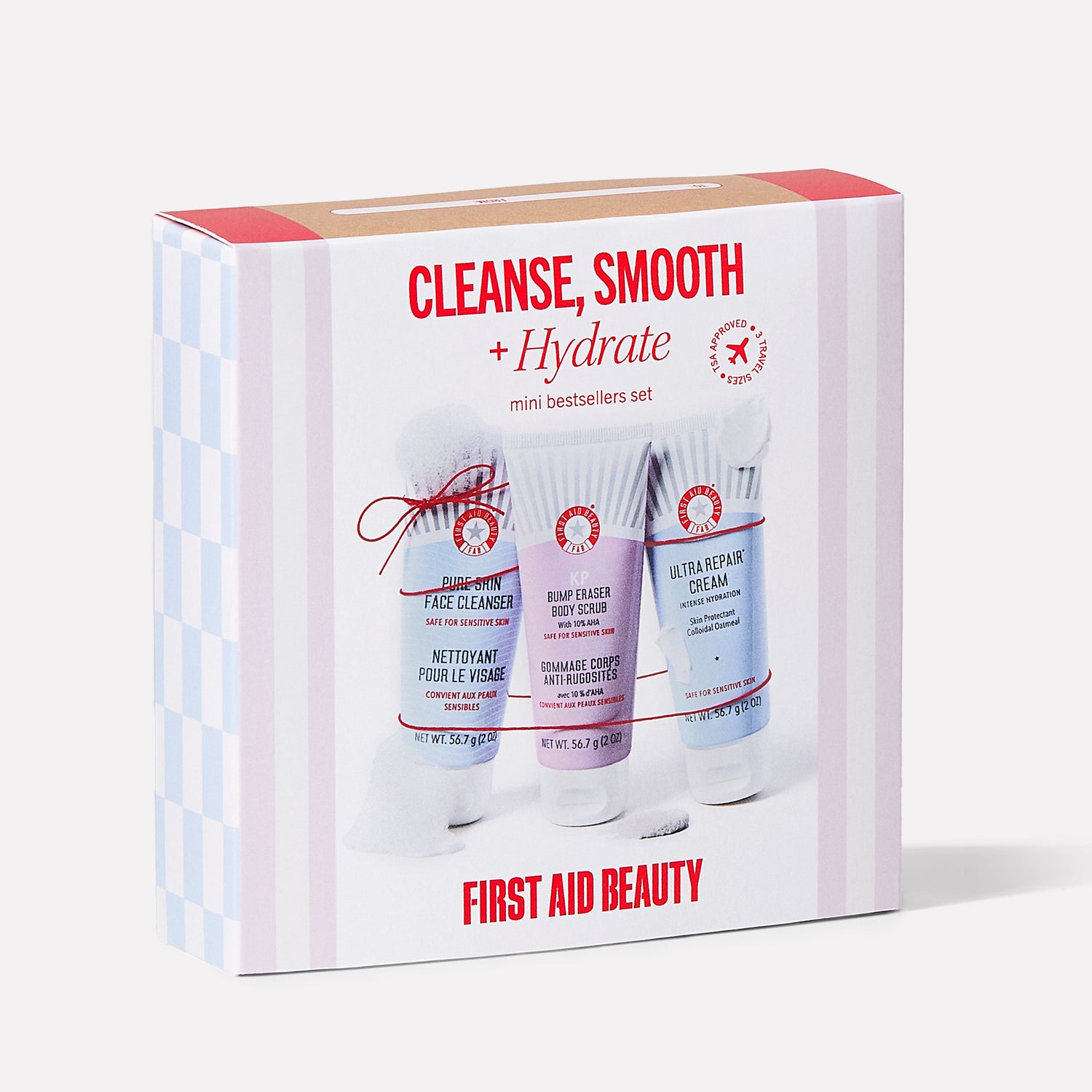 The box contains three skincare products labeled "Pure Skin Face Cleanser," "KP Bump Eraser Body Scrub," and "Ultra Repair Cream." Text: "CLEANSE, SMOOTH + Hydrate mini bestsellers set," "FIRST AID BEAUTY."