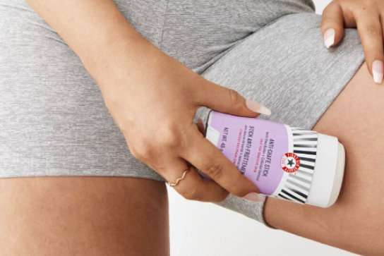 Woman applying Anti-Chafe Stick product to leg