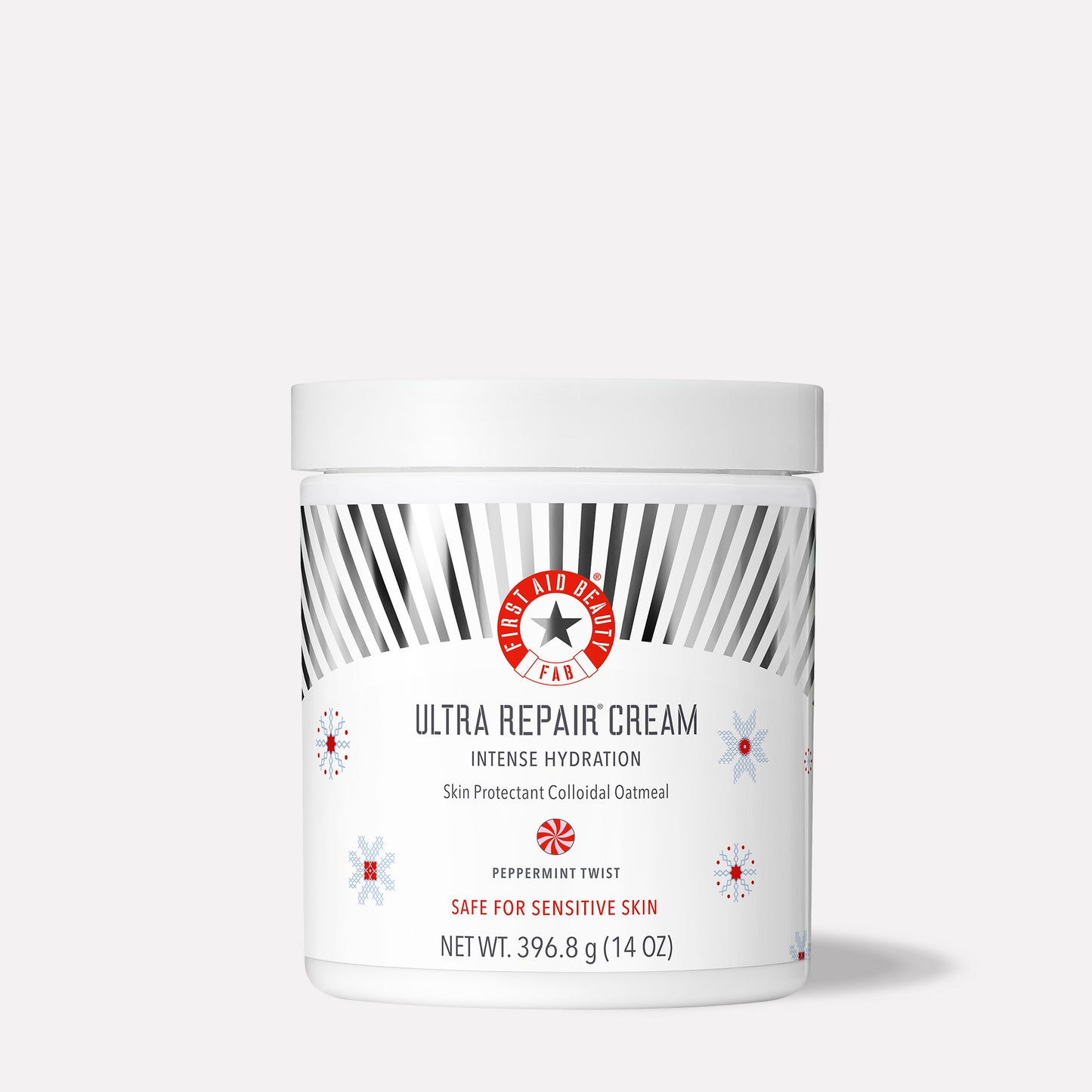 A white jar labeled "First Aid Beauty Ultra Repair Cream." It provides intense hydration with colloidal oatmeal, peppermint twist fragrance, safe for sensitive skin, 396.8 g (14 oz). Decorated with grey rays and snowflake patterns.